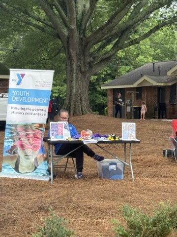 Woman sitting at a table with a pull up banner next to her advertising Youth Development.