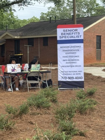 Two women seated at a booth with a vertical banner for a Senior Benefits Specialist. 