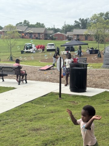 Families outside with bubbles, booths, and tents in the background. 